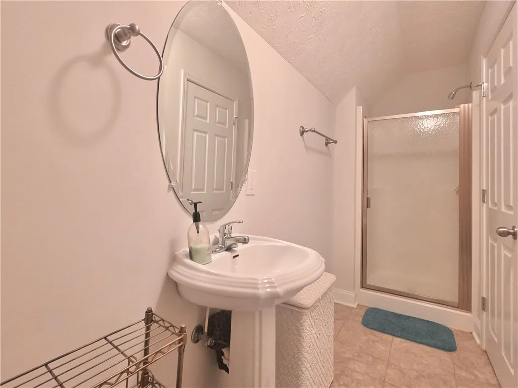 A classic pedestal sink paired with a glass-enclosed shower highlights this functional bathroom space.