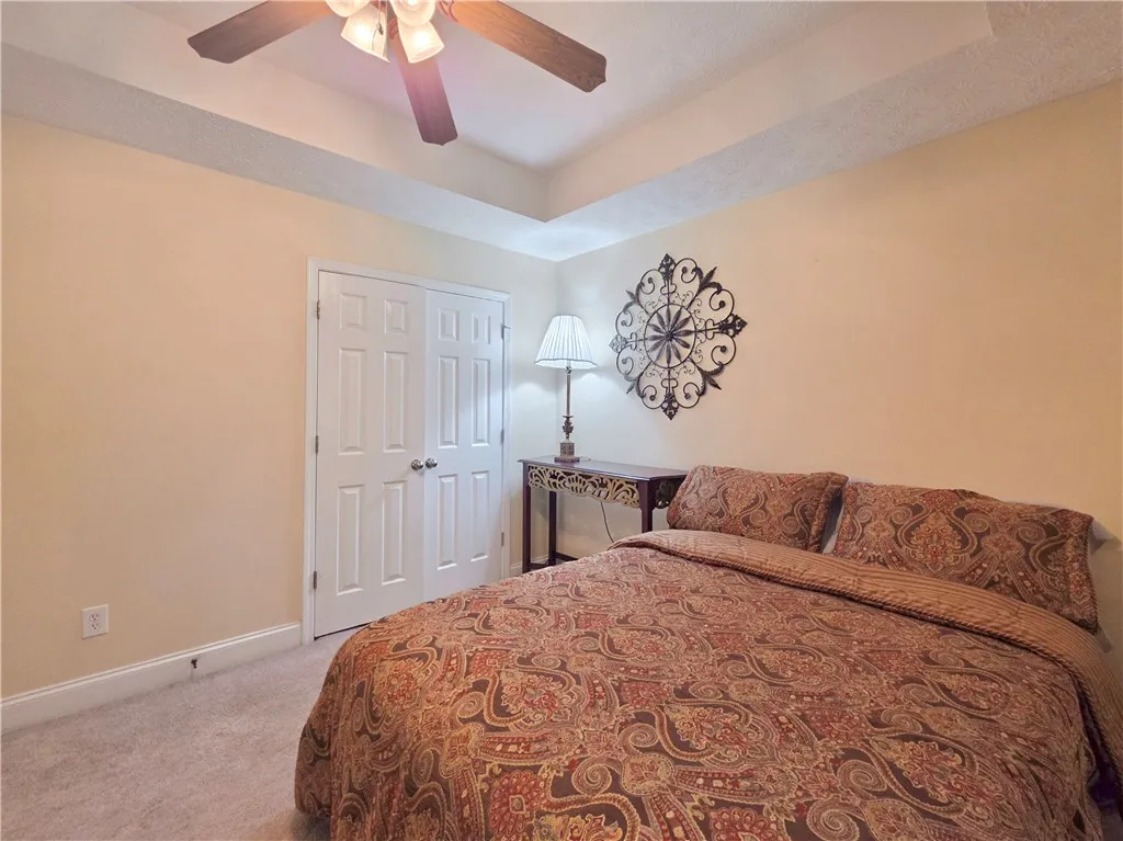 An elegant tray ceiling and soft carpeting define this inviting bedroom space.
