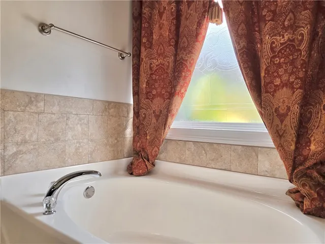 Tiled walls and a frosted window surround this deep, relaxing bathtub.