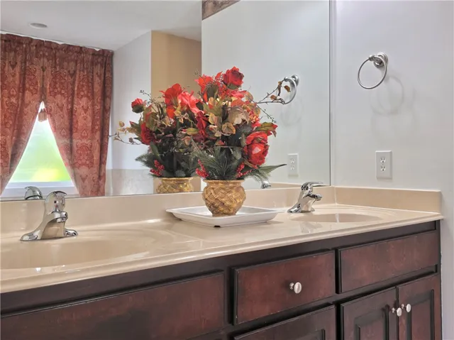A spacious double vanity features classic dark cabinetry and a expansive mirror reflecting the room.