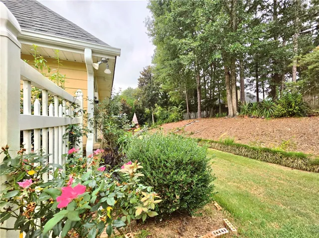 Lush landscaping and mature trees border a private, grassy side yard.