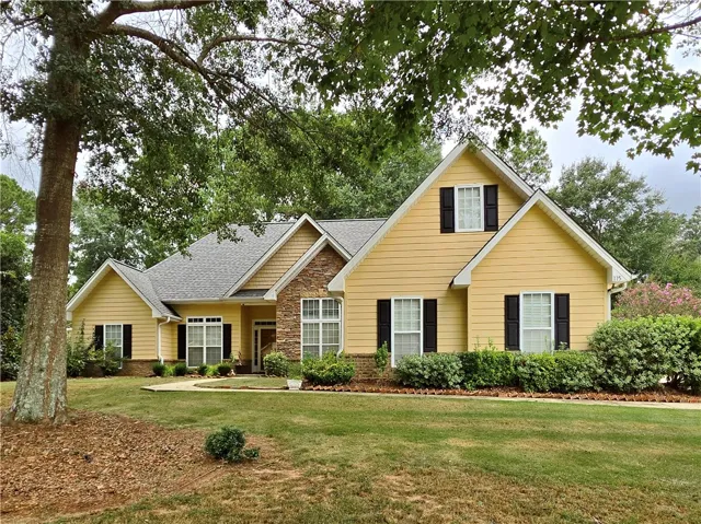 Mature trees frame a charming multi-gabled facade accented with classic stone and siding detail.