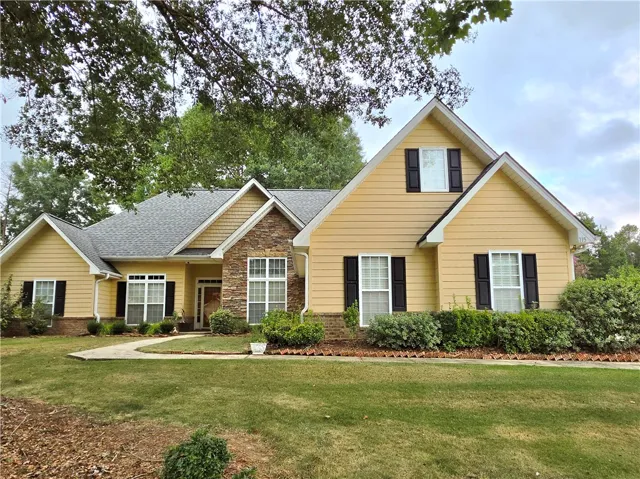 An inviting facade displays neat stone accents alongside a well-kept front lawn.