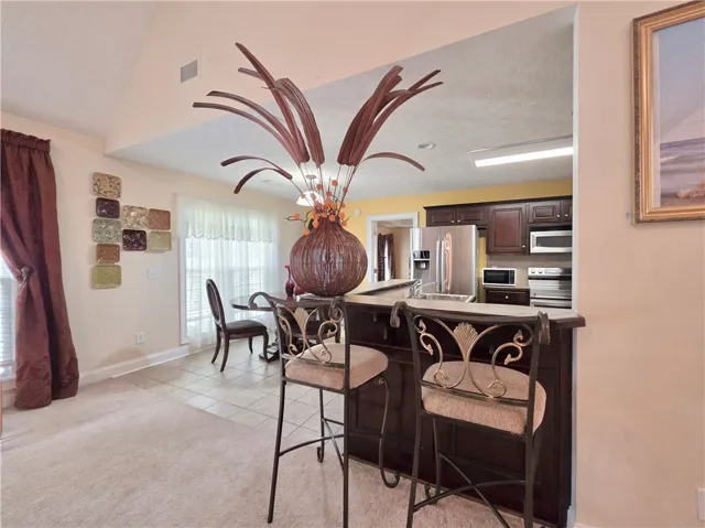 An open breakfast bar overlooks the kitchen beneath high vaulted ceilings.