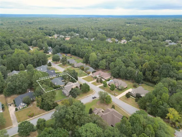 An aerial perspective showcases a spacious lot nestled in a quiet, tree-lined neighborhood.