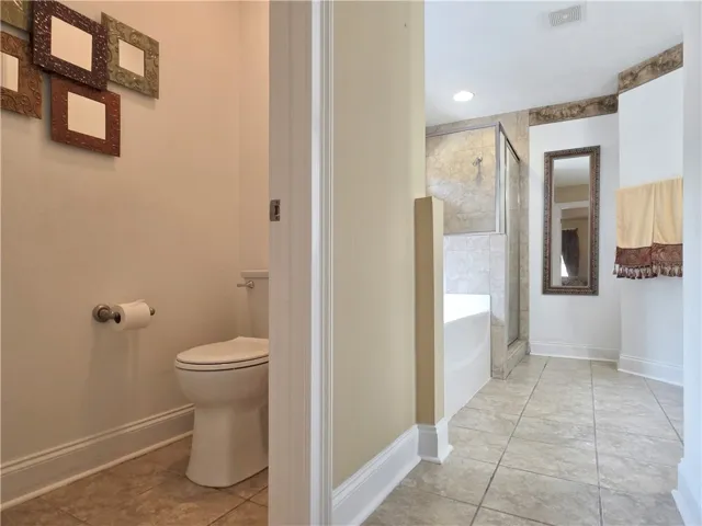 Crown molding highlights the high ceilings of this master bathroom with tile flooring.
