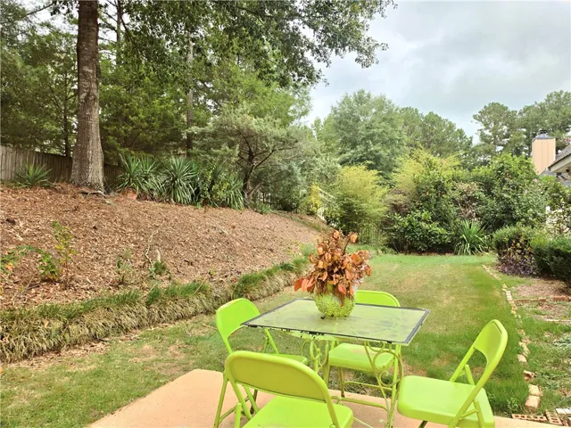 Mature trees and lush greenery frame a peaceful backyard lawn and patio area.
