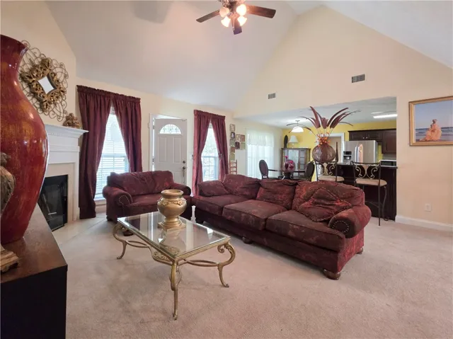 A spacious living room features soaring vaulted ceilings and a cozy fireplace.