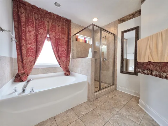 A deep soaking tub sits adjacent to a glass-enclosed walk-in shower with tile surrounds.