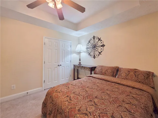 An elegant tray ceiling and soft carpeting define this inviting bedroom space.