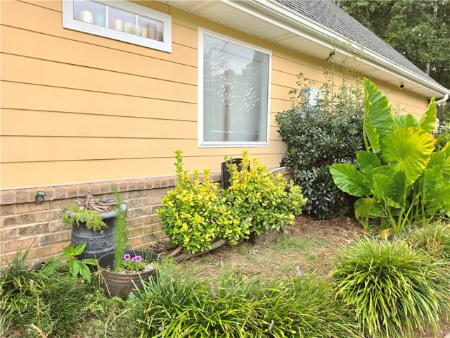 Lush landscaping complements the siding and brick foundation of this charming exterior.