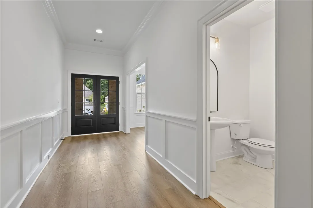 Crisp wainscoting and warm wood floors define this welcoming entry with an adjacent half bath.