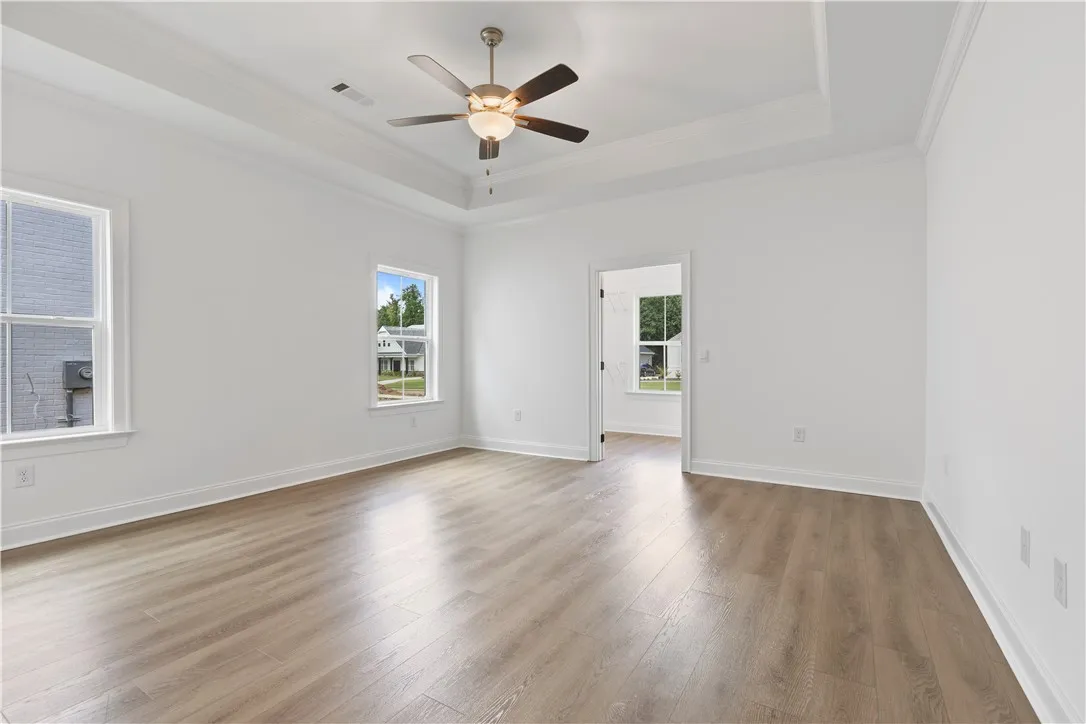 Clean lines and a tray ceiling define this open, airy primary bedroom.