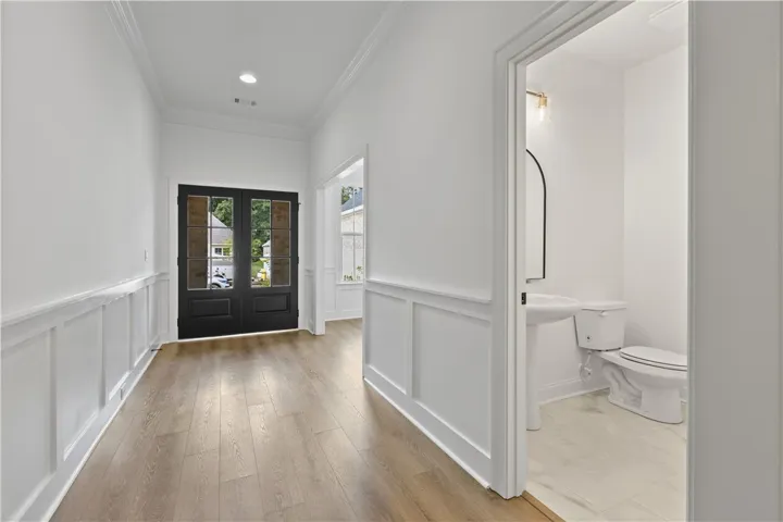 Crisp wainscoting and warm wood floors define this welcoming entry with an adjacent half bath.