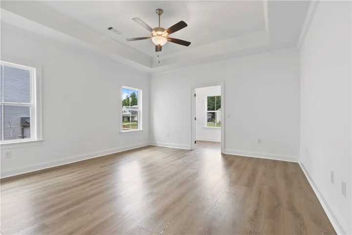 Clean lines and a tray ceiling define this open, airy primary bedroom.