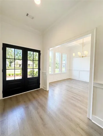 Hardwood floors and crisp wainscoting define this welcoming entryway opening to a formal dining room.