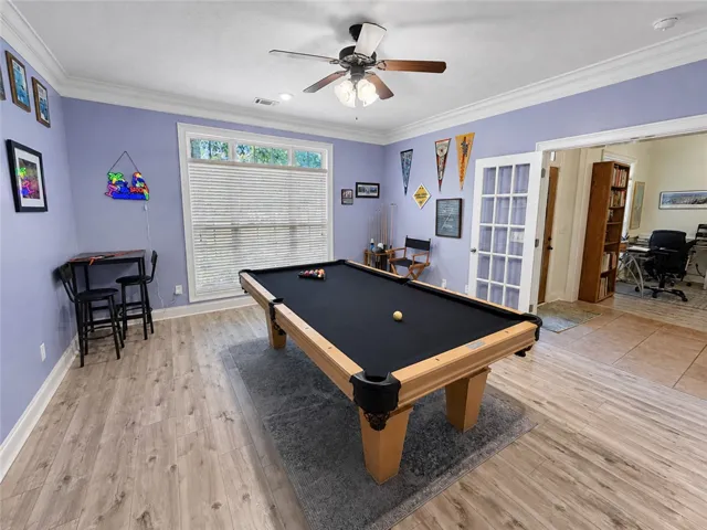 Gleaming wood-look floors, crown molding, and classic French doors elevate this versatile recreation space.