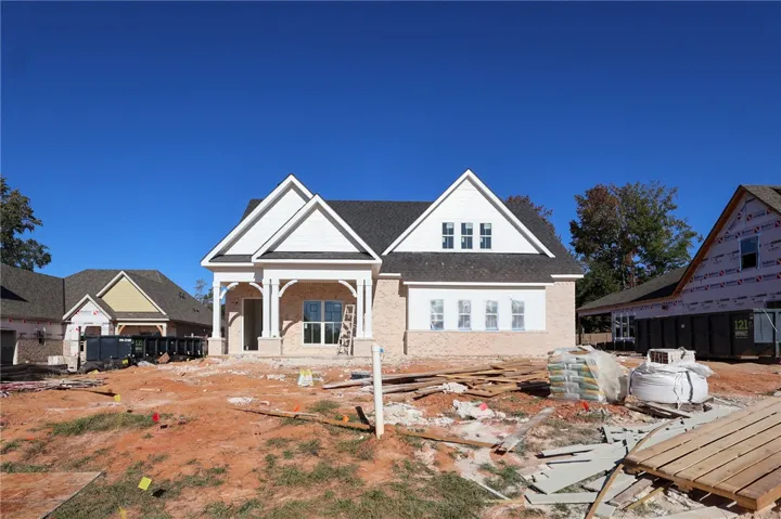 Crisp white gables and classic brick siding define this new construction residence under a clear sky.