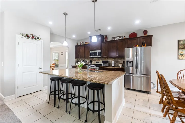 Rich wood cabinetry and polished stone countertops elevate this airy, tile-floored cooking space.