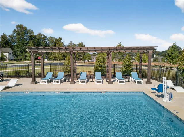 An inviting pool area awaits, offering relaxation under a stylish pergola.