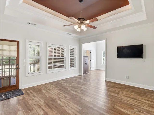 Primary bedroom with trey ceiling, LVP flooring, and access to covered back porch
