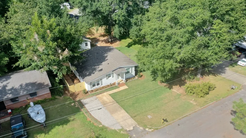 Mature trees frame a welcoming ranch home with a spacious front lawn and driveway.