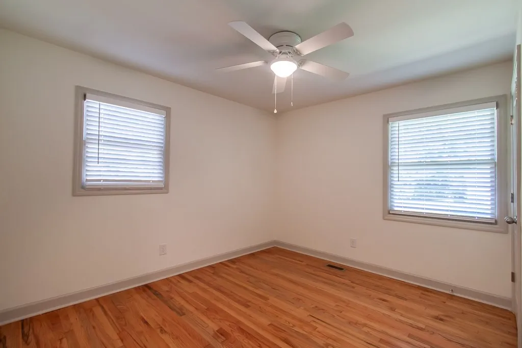 Rich hardwood floors anchor this light-filled room framed by classic window molding.