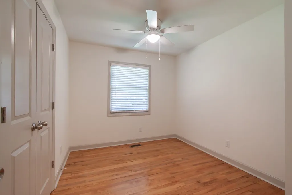 Rich hardwood flooring anchors this versatile bedroom space featuring a central window.