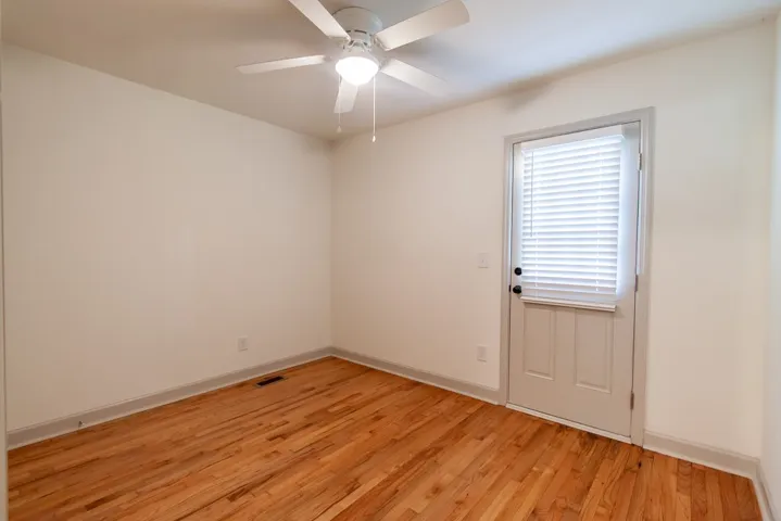 Rich hardwood flooring anchors this versatile space, featuring a private exterior exit door.