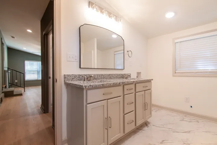 Fine stone countertops elevate this modern double vanity bathroom with premium marble look flooring.
