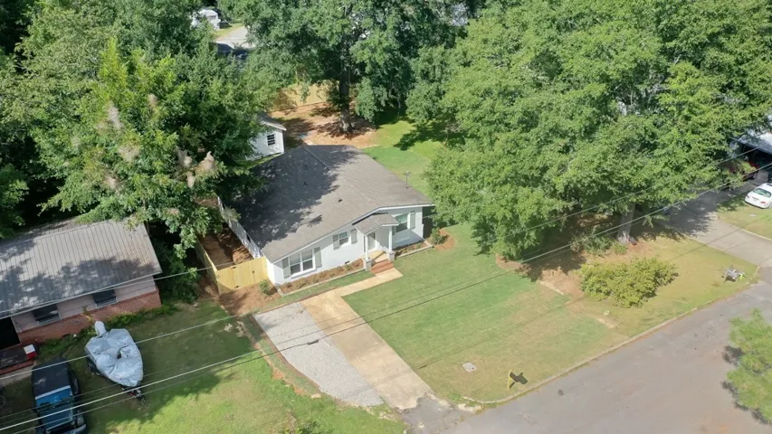 Mature trees frame a welcoming ranch home with a spacious front lawn and driveway.