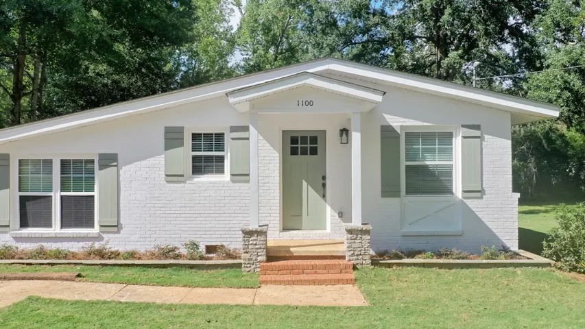 A welcoming front porch steps up to the entrance of this classic brick ranch home.