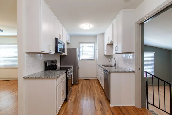 Gleaming hardwood floors and stone countertops define this efficiently designed galley kitchen.