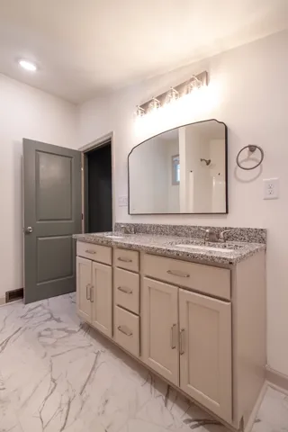Polished stone countertops pair with marble-look flooring in this refreshed secondary bath.