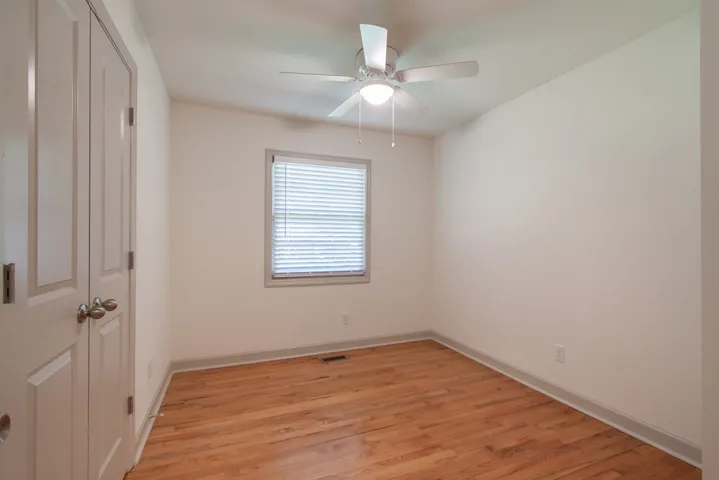 Rich hardwood flooring anchors this versatile bedroom space featuring a central window.