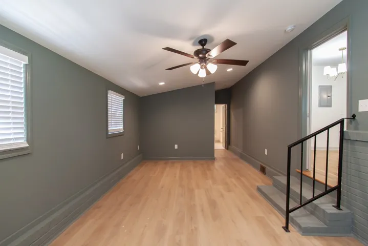 Smooth wood floors anchor this versatile living space featuring sloped ceilings and recessed lighting.