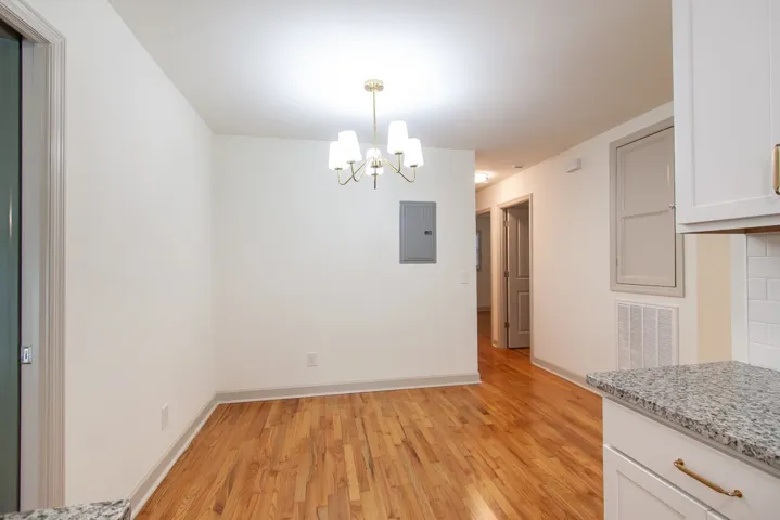 Rich hardwood flooring anchors this versatile space, highlighted by a classic hanging light fixture.
