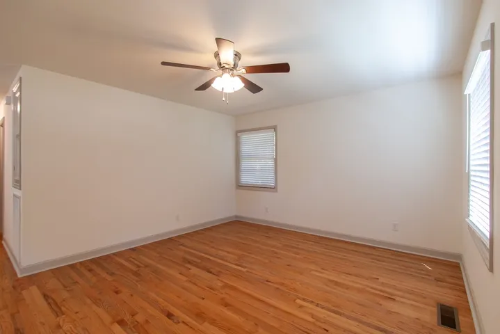 Polished hardwood floors and crisp neutral walls create a versatile canvas in this clean bedroom.