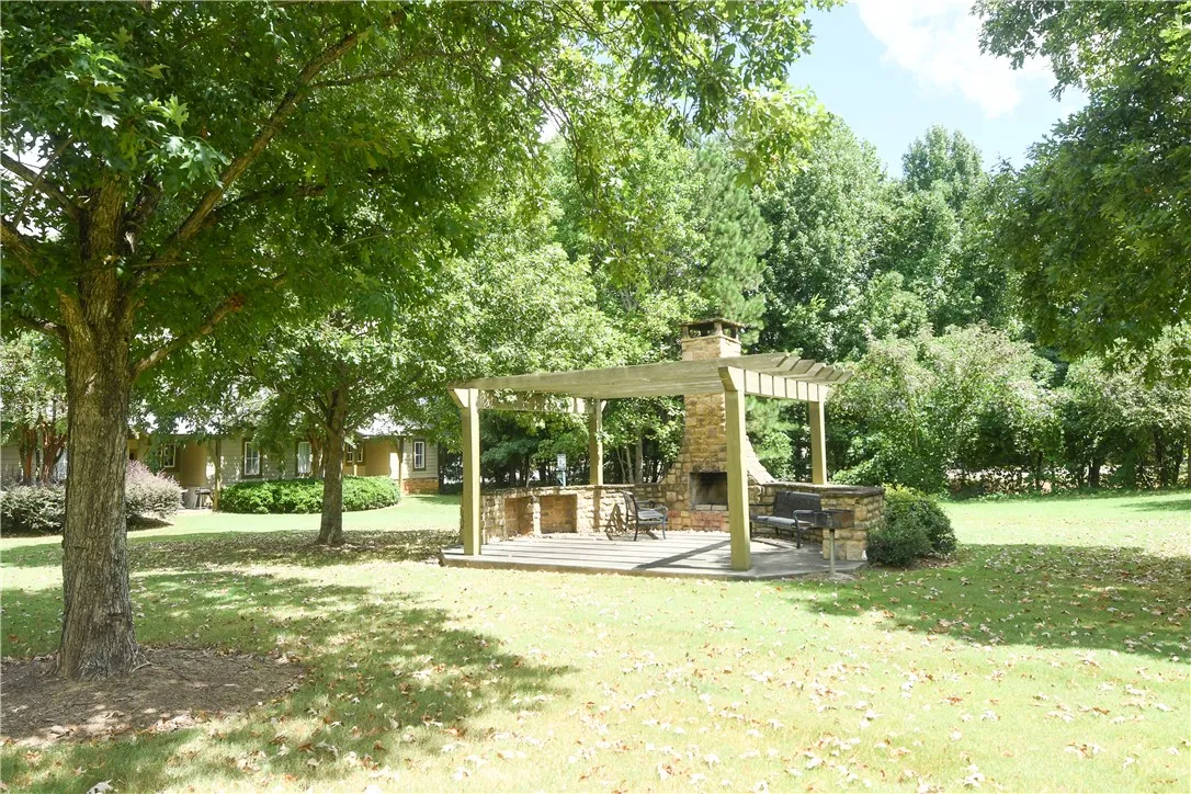 A stone fireplace and wooden pergola create an inviting outdoor space.