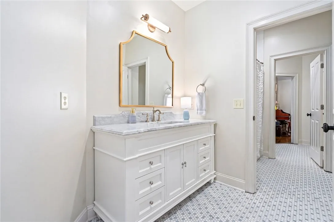 Polished stone countertops and classic patterned tile floors in this refined jack-n-jill bathroom space.