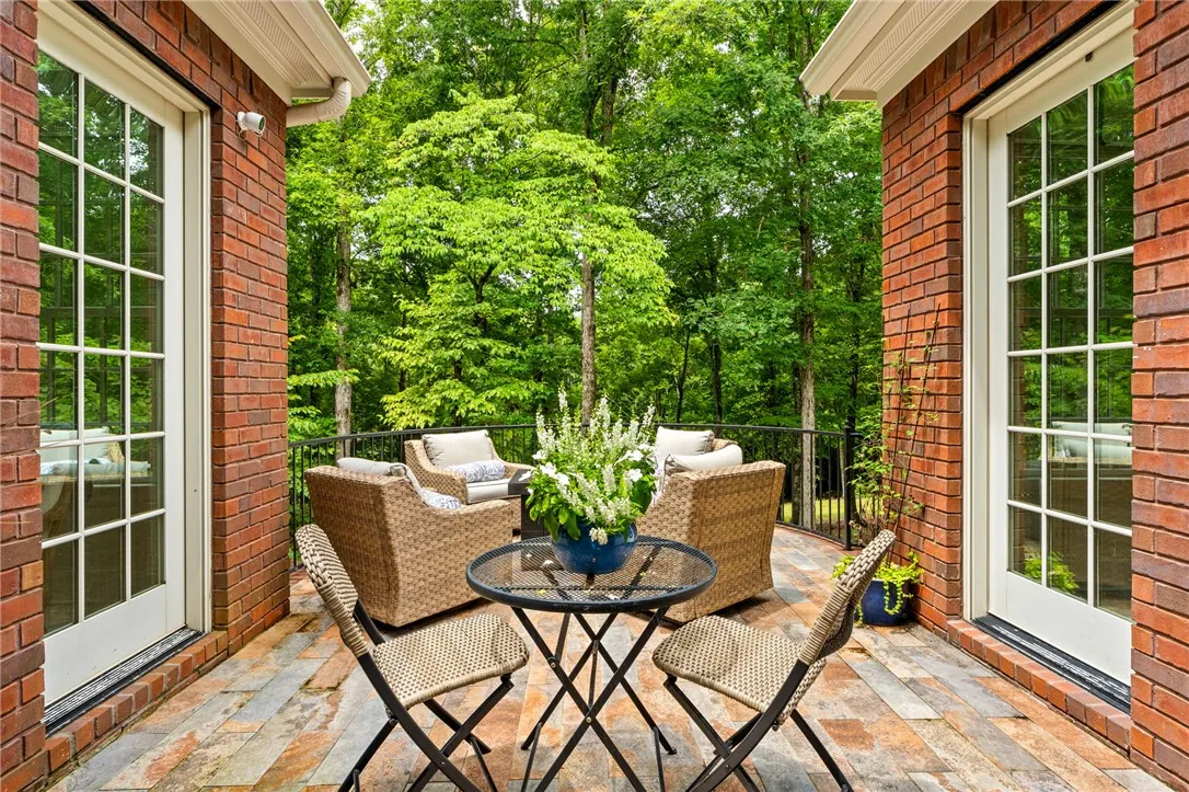 Lush woodland views provide a serene backdrop for this stone-tiled patio space.