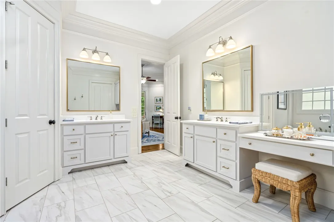 Crown molding and tiled floors elevate this spacious bathroom with dual vanities.