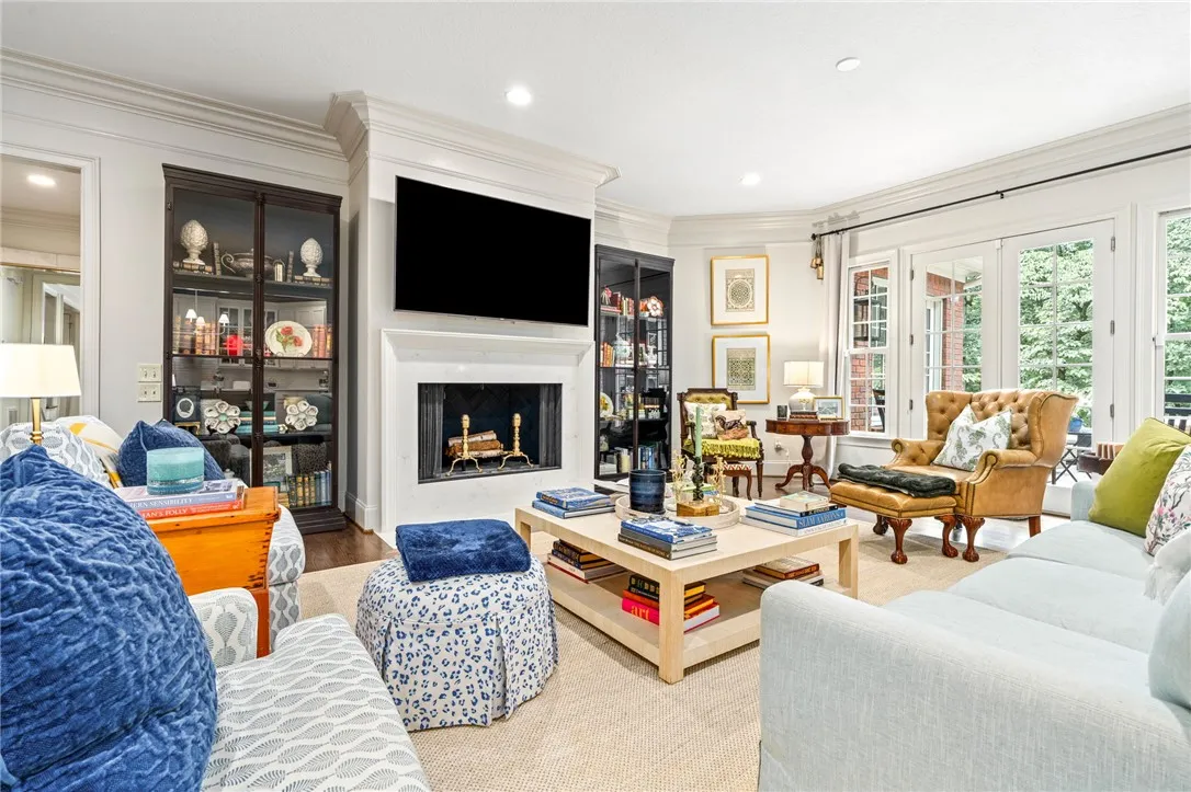 Elegant crown molding and glass doors frame this comfortable living room anchored by a woodburning fireplace.