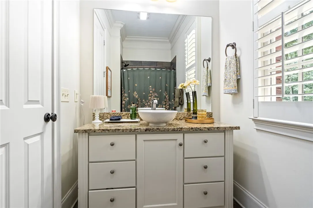 Polished granite counters and classic plantation shutters enhance this full bathroom.