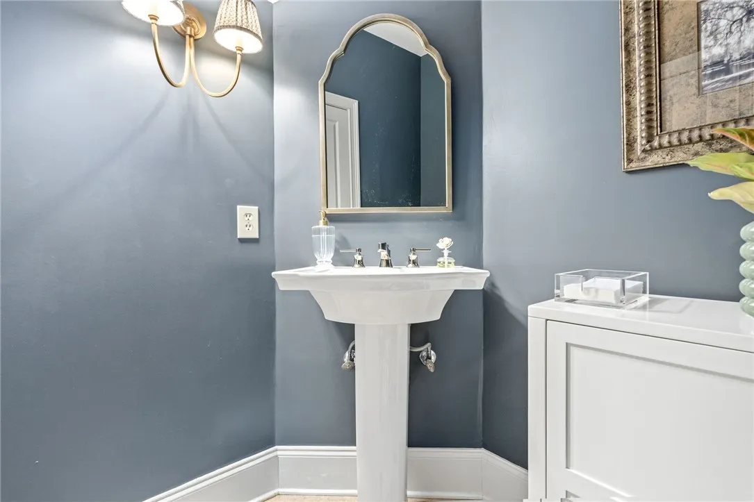 A classic pedestal sink anchors this classic main floor powder room setup.