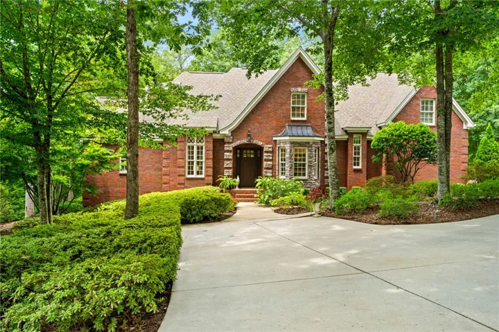 Mature trees frame a classic brick exterior with a welcoming driveway.