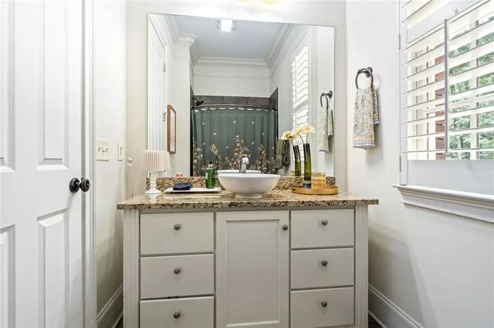 Polished granite counters and classic plantation shutters enhance this full bathroom.