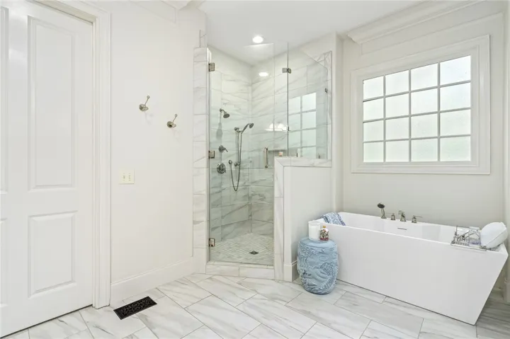 Elegant tile floors and a glass-enclosed walk-in shower create this private spa-like space.