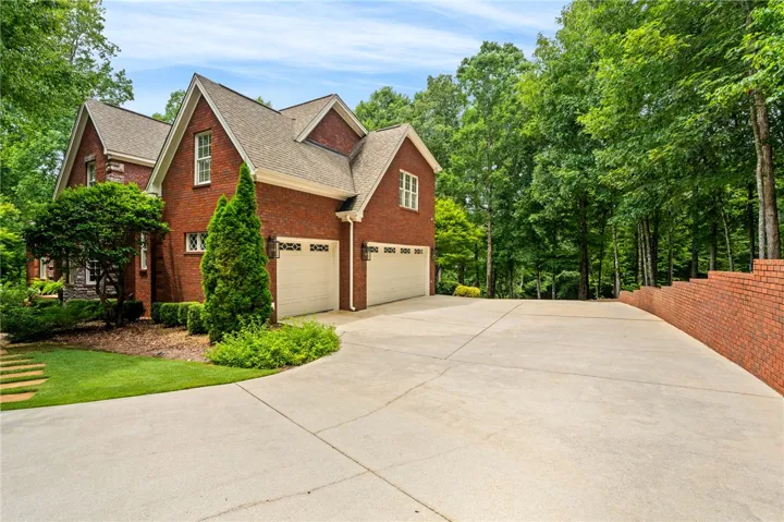 Tall gables and classic brick siding frame the extensive driveway of this woodland estate with a 3-car garage.