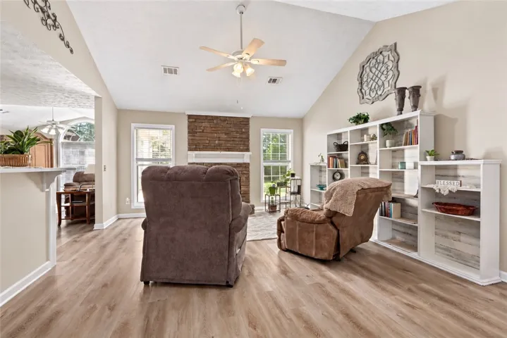 A stone fireplace anchors this living space highlighted by vaulted ceilings and wood-look flooring.